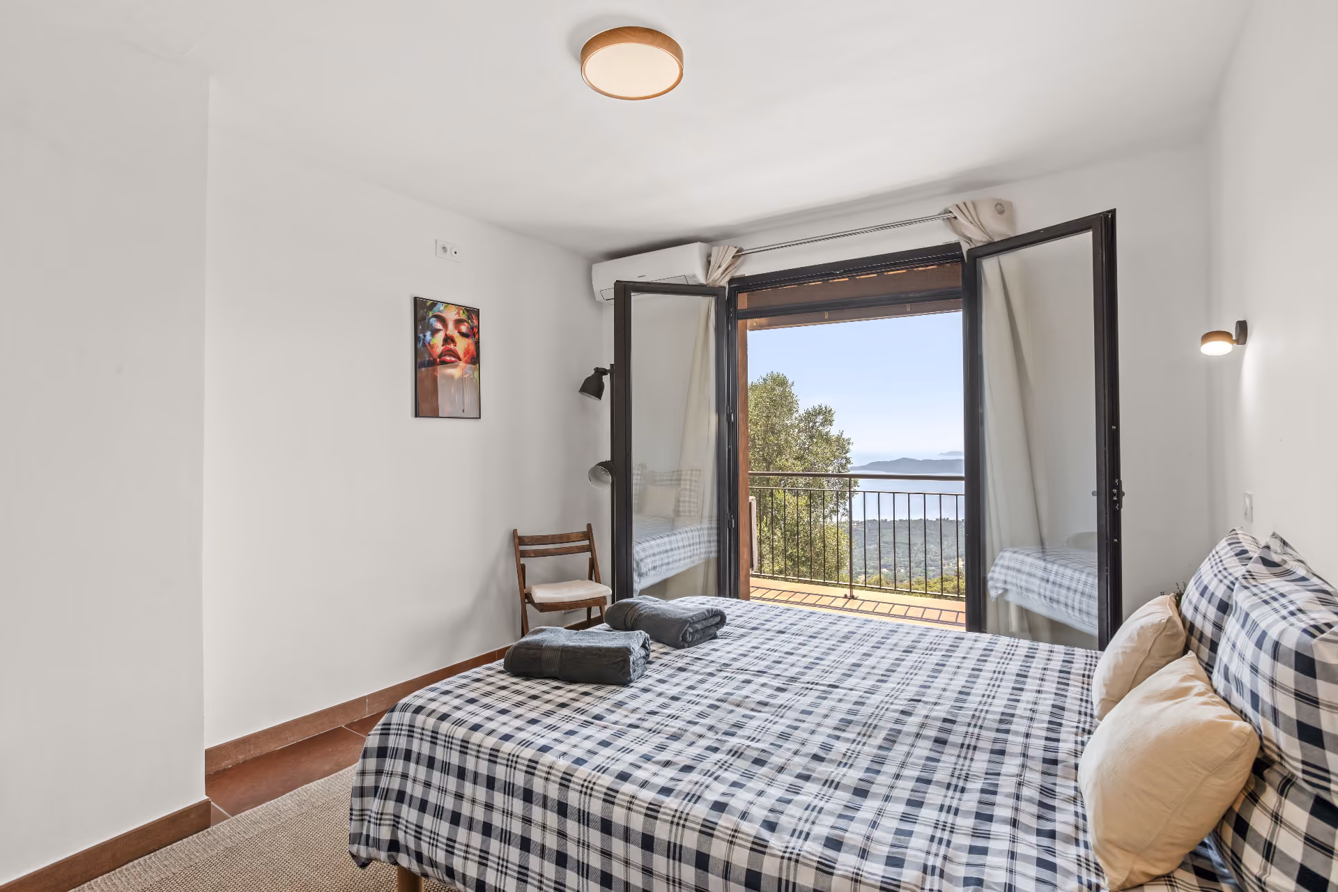 Una Camera with floral sofa, wooden armoire, chandelier, and open windows showing green trees in Castello Higo rooms