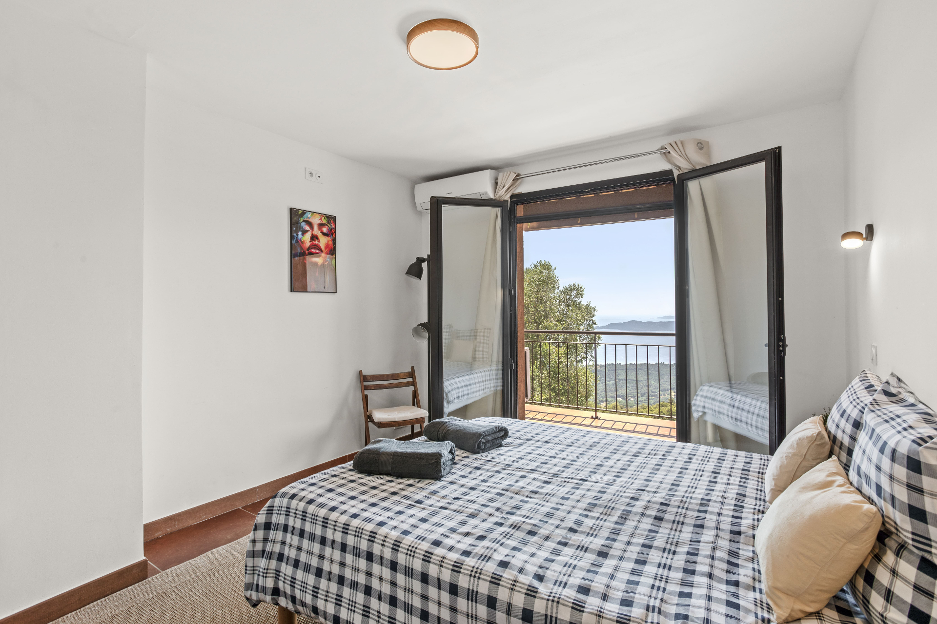 Una Camera with floral sofa, wooden armoire, chandelier, and open windows showing green trees in Castello Higo rooms