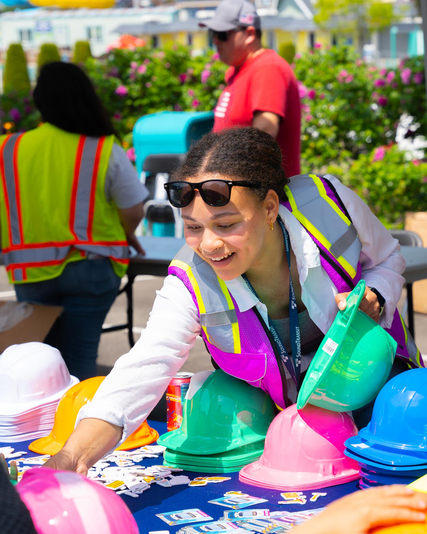 A PRR staffer in a safety vest setting out hard hats and activity materials at an outdoor community event
