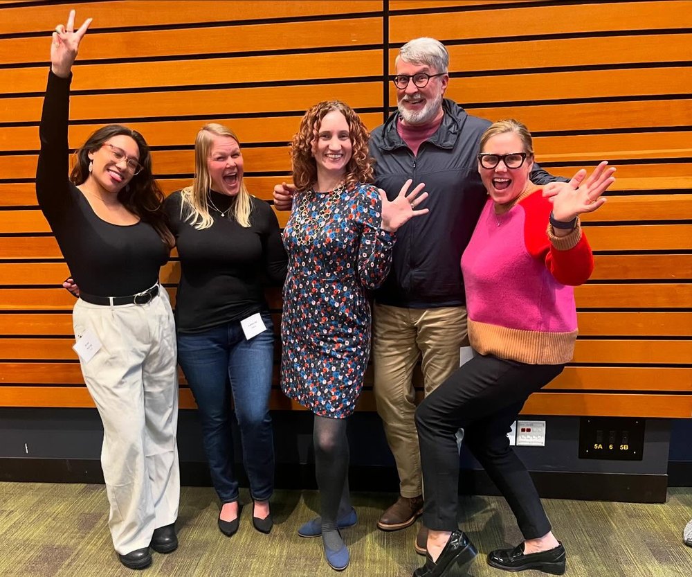 Five PRR staff members cheer and pose together at a conference.
