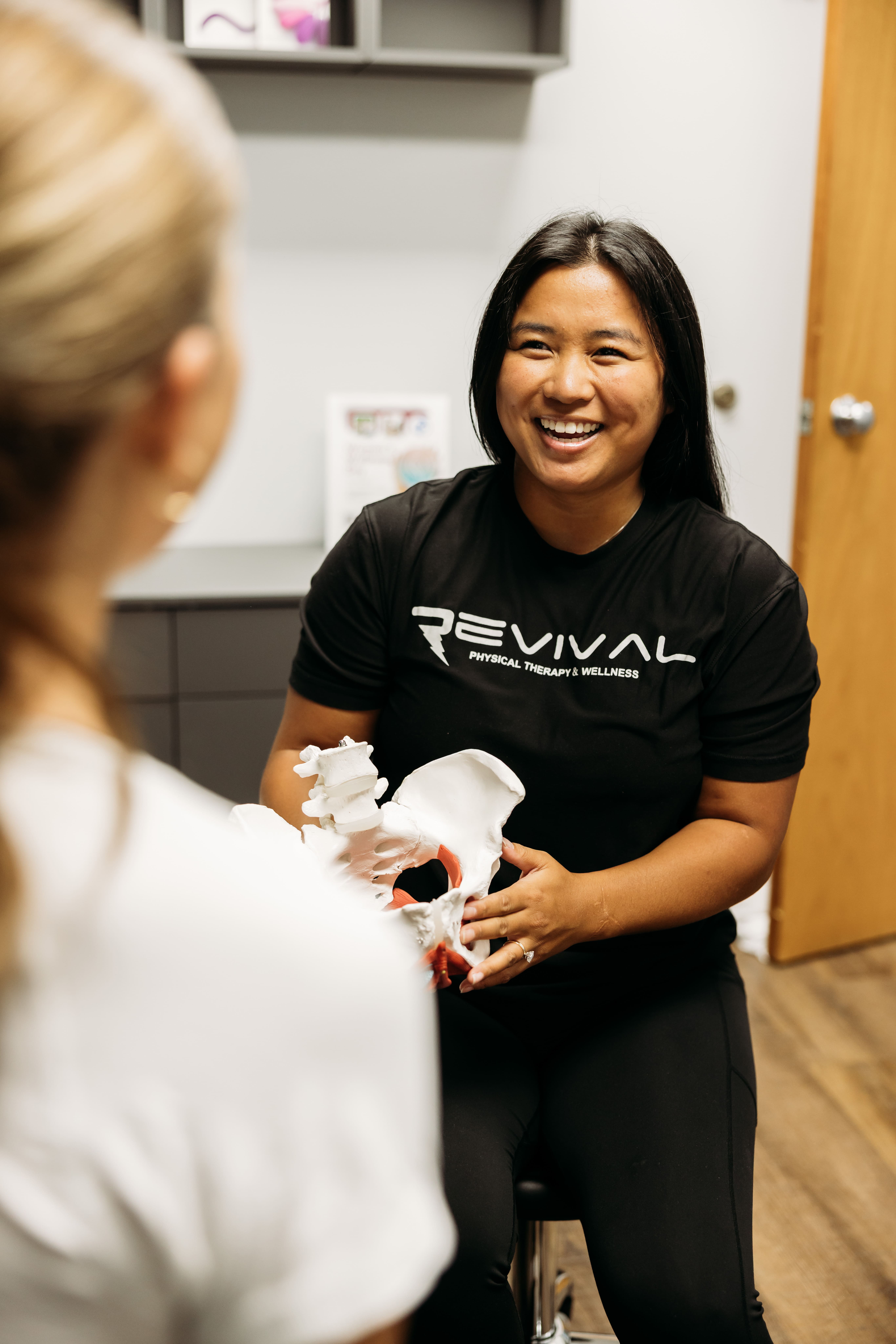 Physical therapist explaining a pelvic anatomy model to a patient during a consultation.