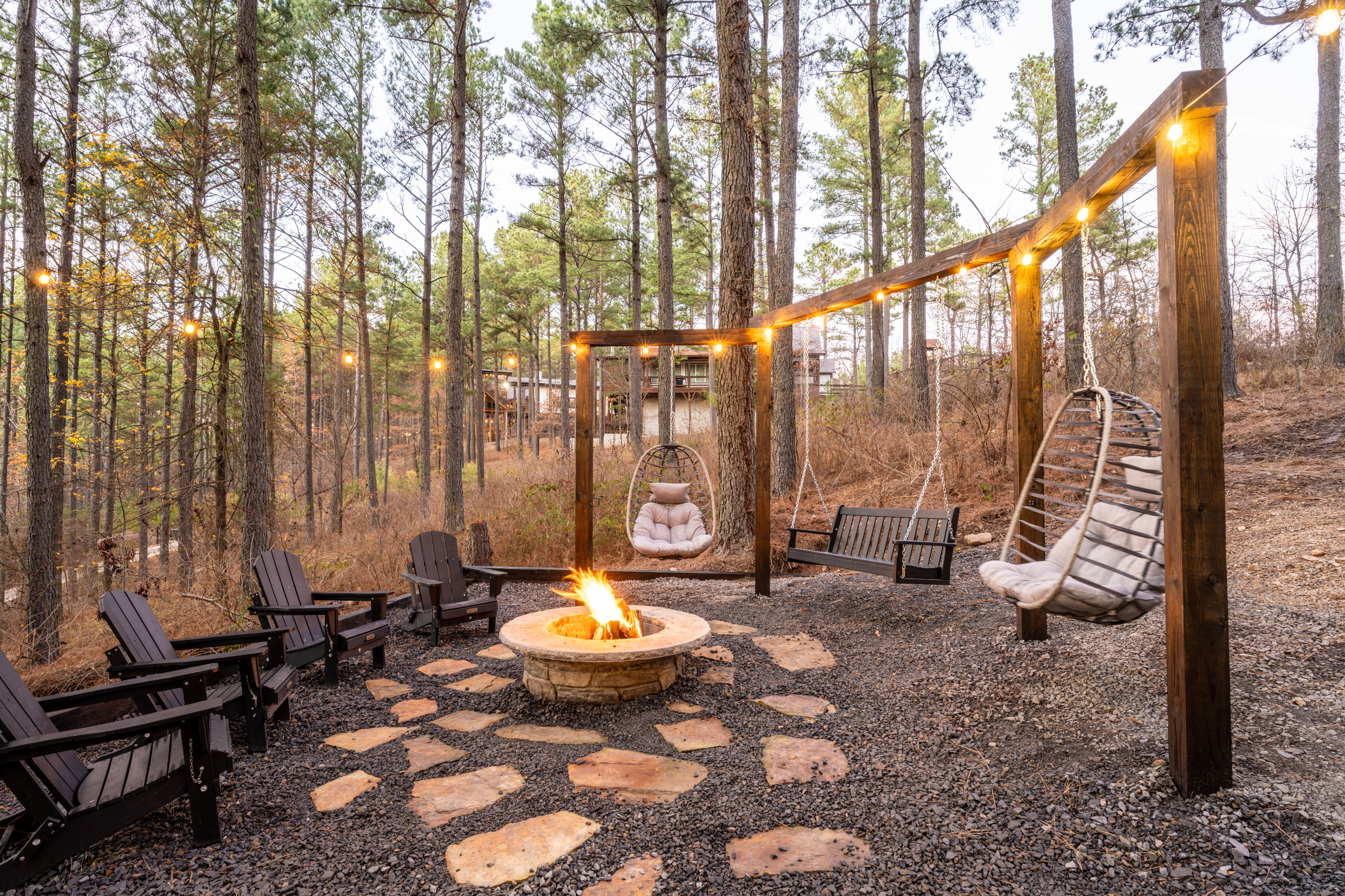 Surrounded by towering trees, you'll love this epic fire pit with cozy modern swings and Adirondack chairs set around. String lights are draped around so you'll never be in the dark unless you choose to turn them off to take in the stars.