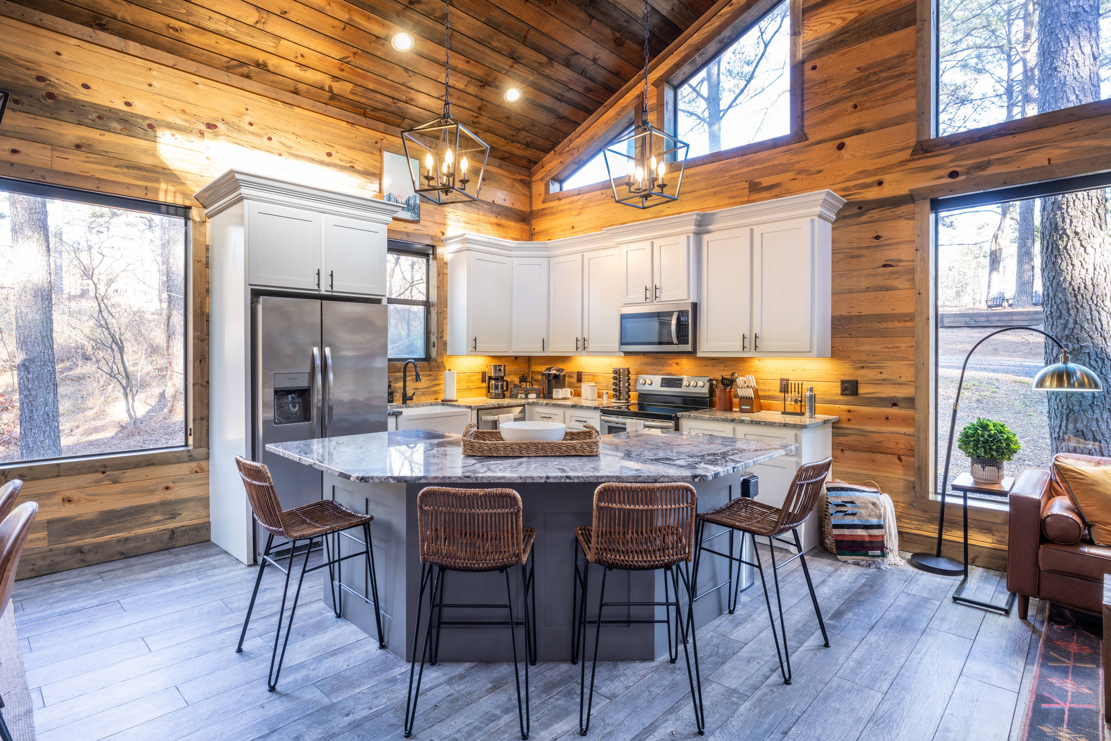 This well-equipped kitchen boasts white cabinetry, modern appliances, and a central island with wicker seating, perfect for socializing while preparing meals. The kitchen is stocked with spices, coffee, and plenty of equipment to cook epic meals!