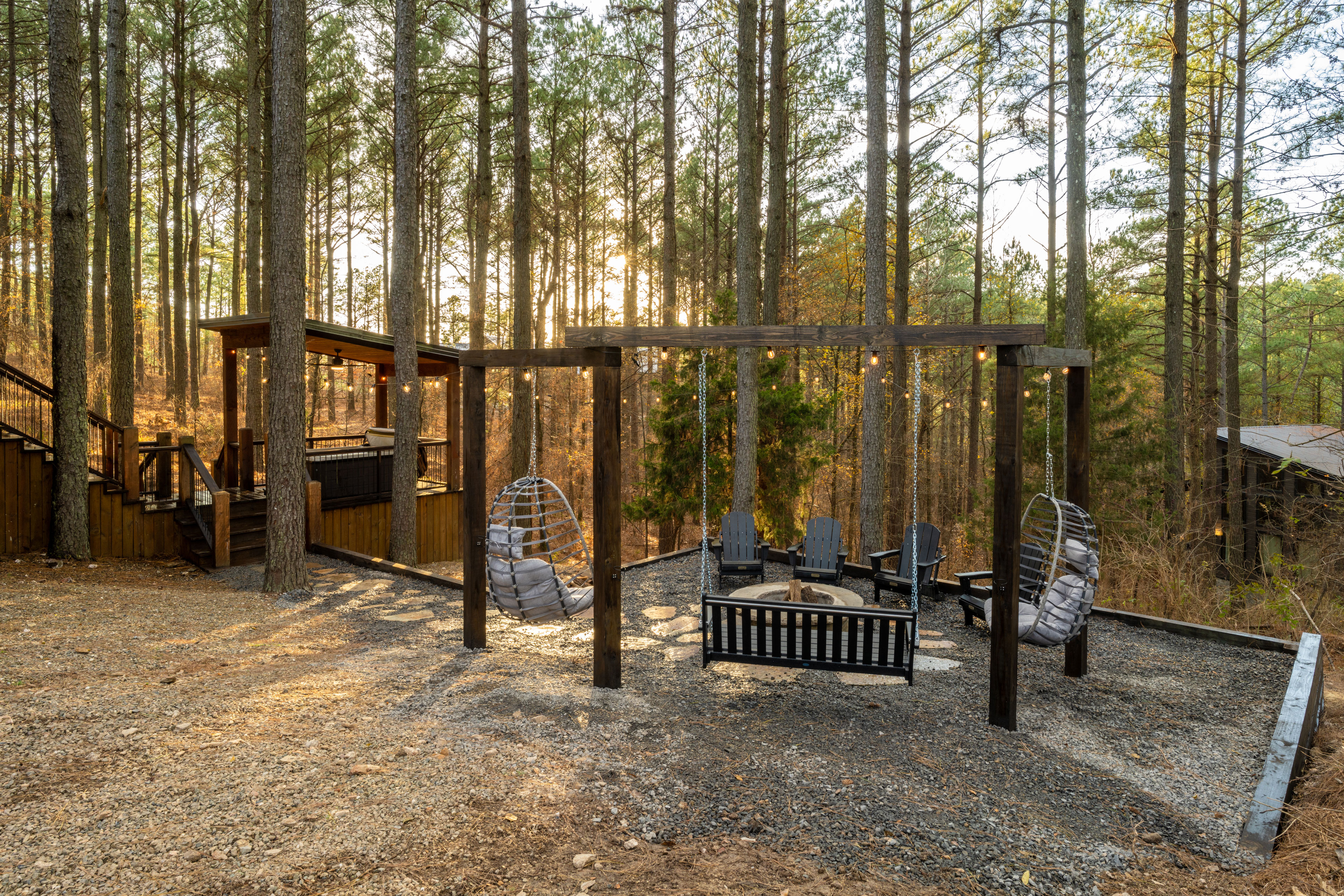 Surrounded by towering trees, enjoy the cozy and modern swings and set up around the stone fire pit. 