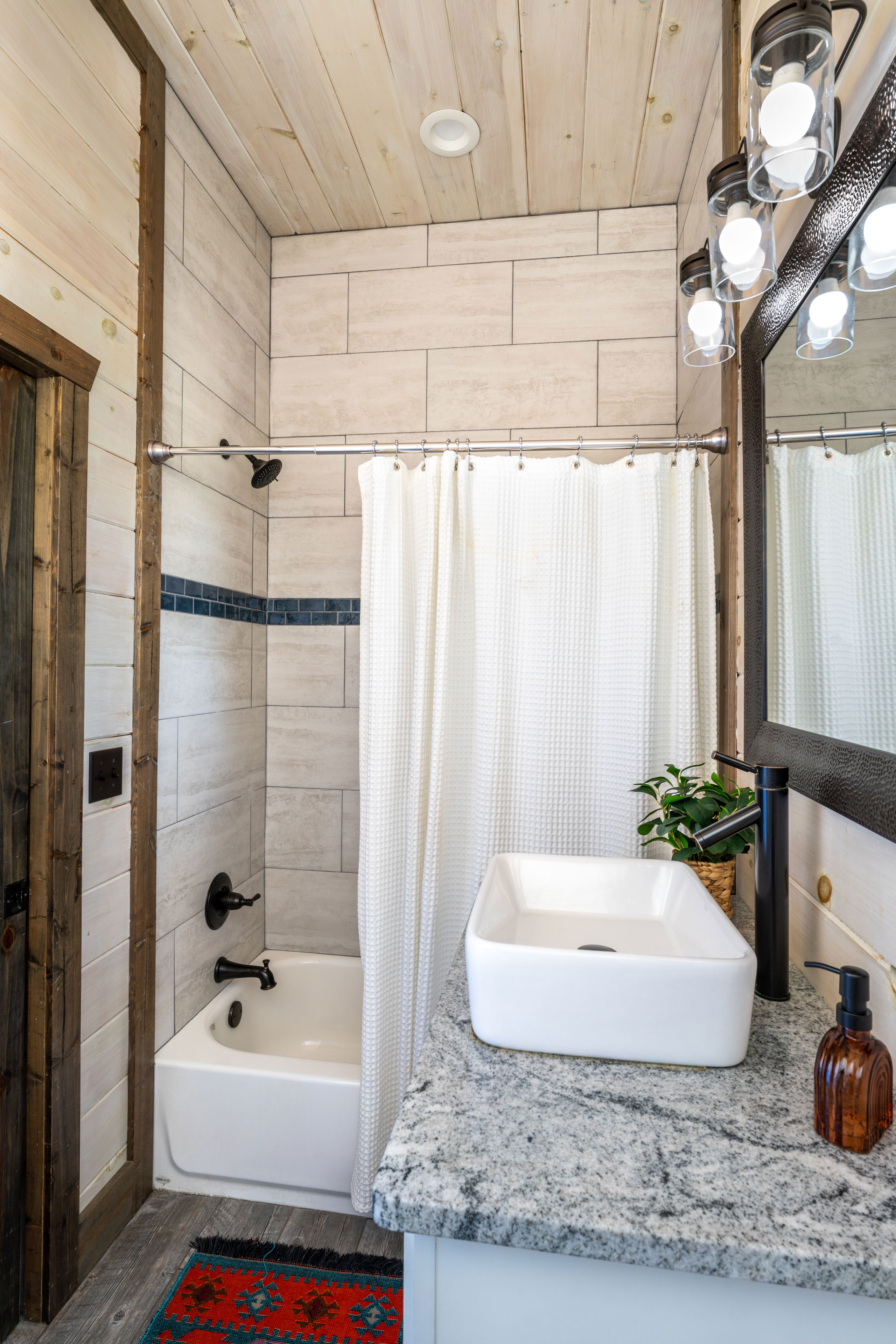 This bathroom, set off from the living room for all to use, features sleek design elements and a bathtub with a showerhead. It's fully stocked with body wash, shampoo, conditioner, towels, and wash cloths for everyone sleeping in the loft.