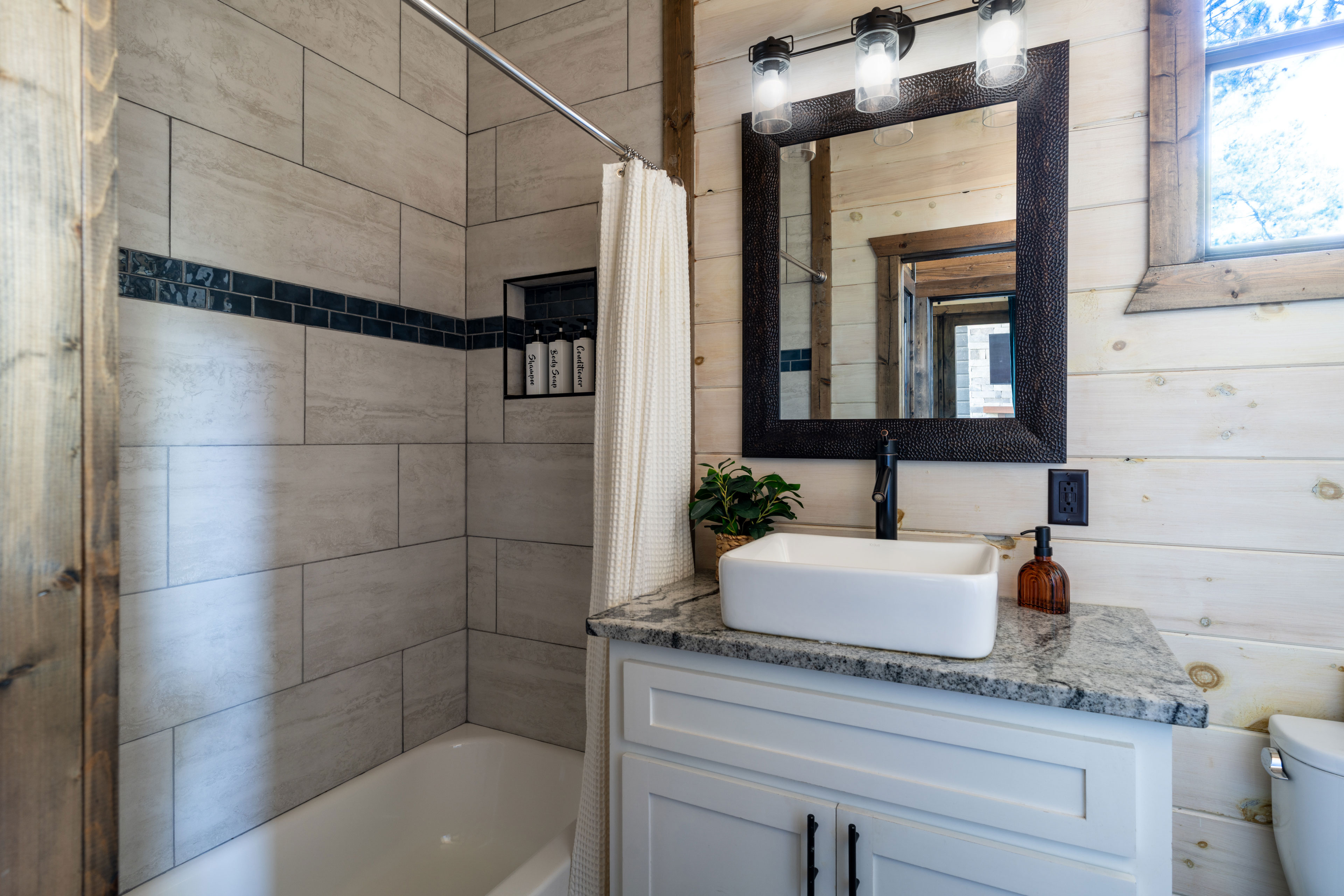 This bathroom, set off from the living room for all to use, features sleek design elements and a bathtub with a showerhead. It's fully stocked with body wash, shampoo, conditioner, towels, and wash cloths for everyone sleeping in the loft.