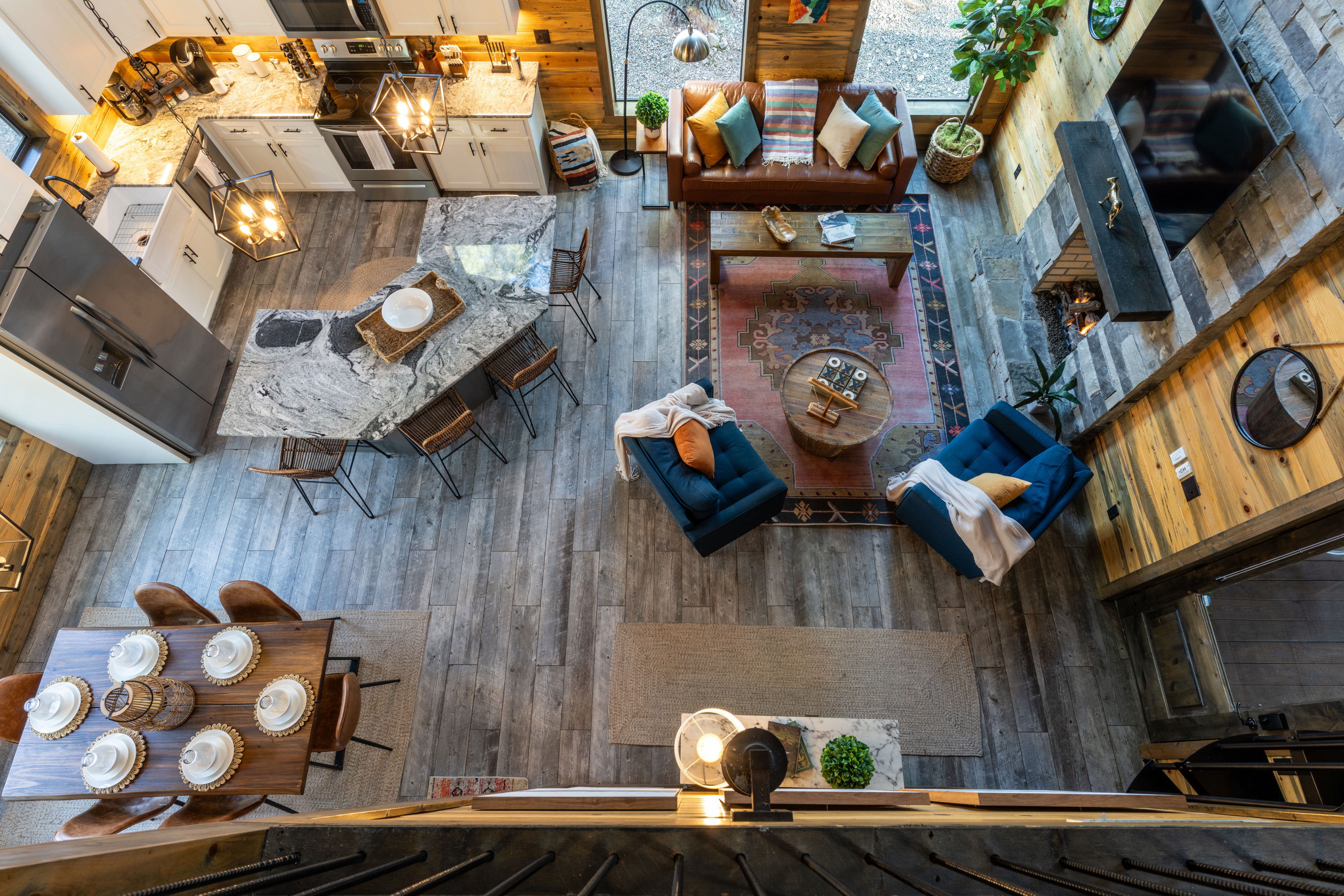 An aerial shot captures the open-plan layout of the living space, integrating the kitchen, dining area, and lounge with stylish decor and natural light. We've outfitted the room with more than enough throw blankets to get cozy. 