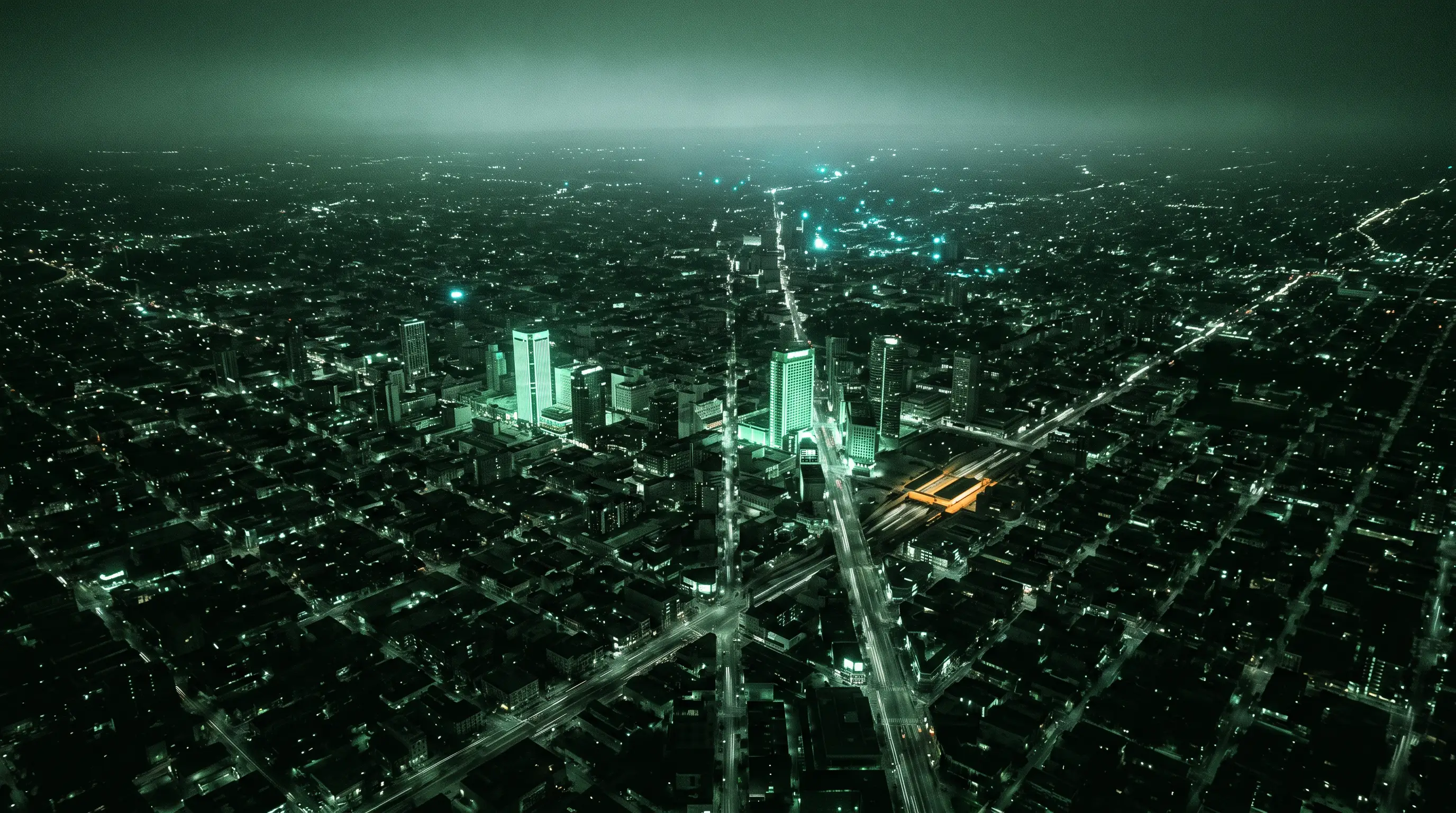 Aerial city grid, a handful of towers lit brilliant, the rest dim