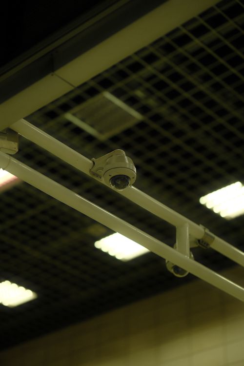 Ceiling-mounted commercial security camera providing video coverage inside a modern facility
