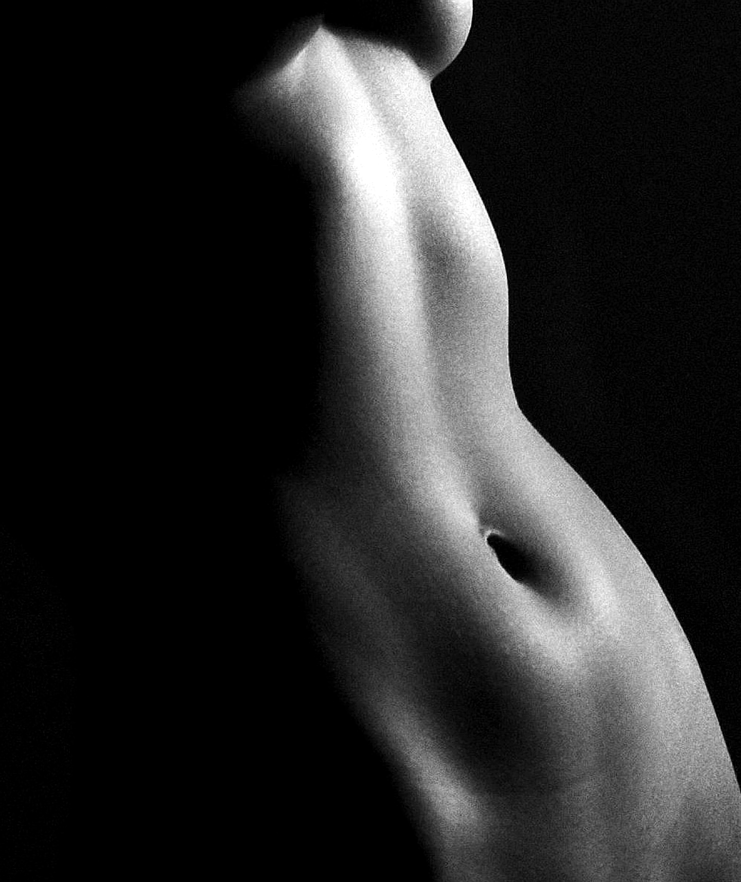 Artistic black and white photo showing the side view of a woman's torso with light and shadow contrast.