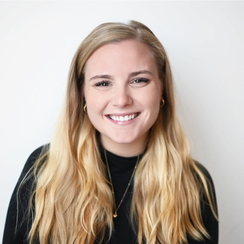 Smiling woman with long blonde hair wearing a black top against a plain white background. Worximity employee