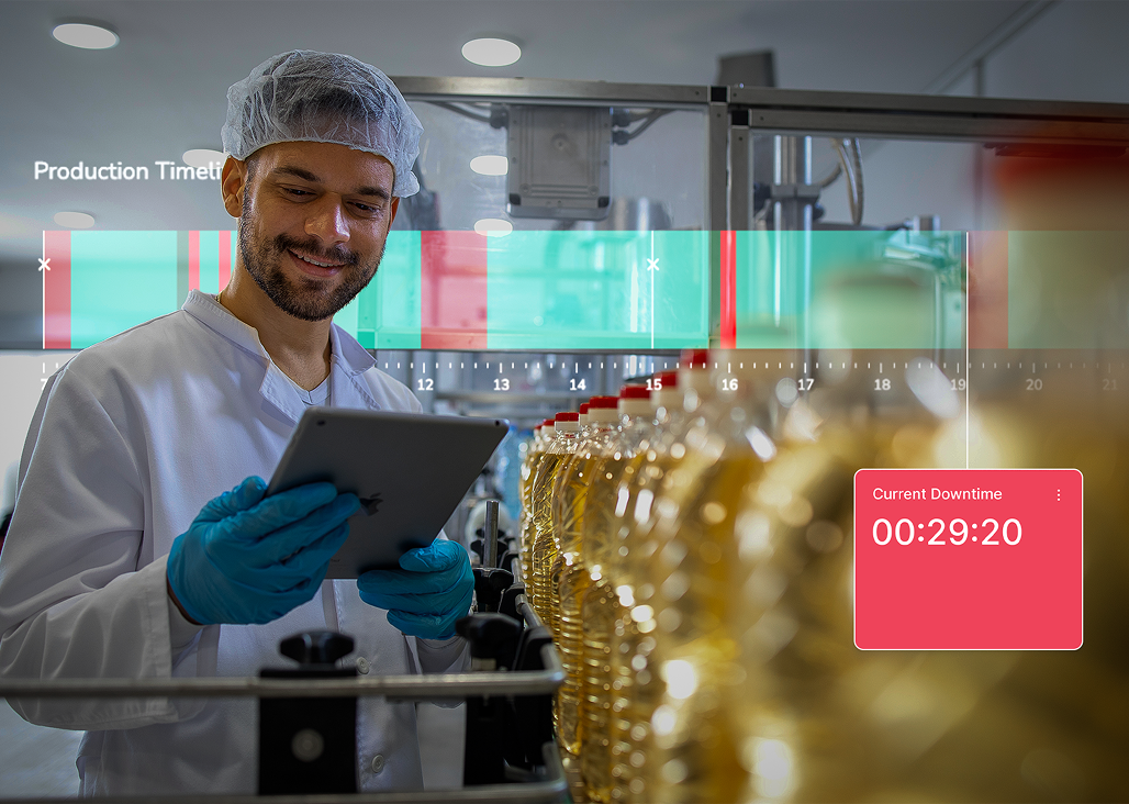 A man wearing a white lab coat, hairnet, and blue gloves is standing in a production facility holding a tablet, monitoring a line of plastic bottles filled with liquid oil. A digital overlay shows a production timeline and a current downtime timer reading 00:29:20.