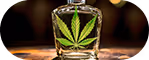 Small glass container with a green cannabis leaf design on a wooden surface.