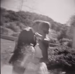Black and white photo of a couple kissing outdoors in a blurry, soft-focus style.