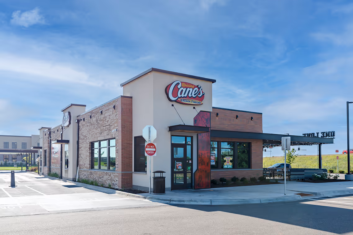 Raising Cane's Chicken Fingers restaurant building with clear blue sky.