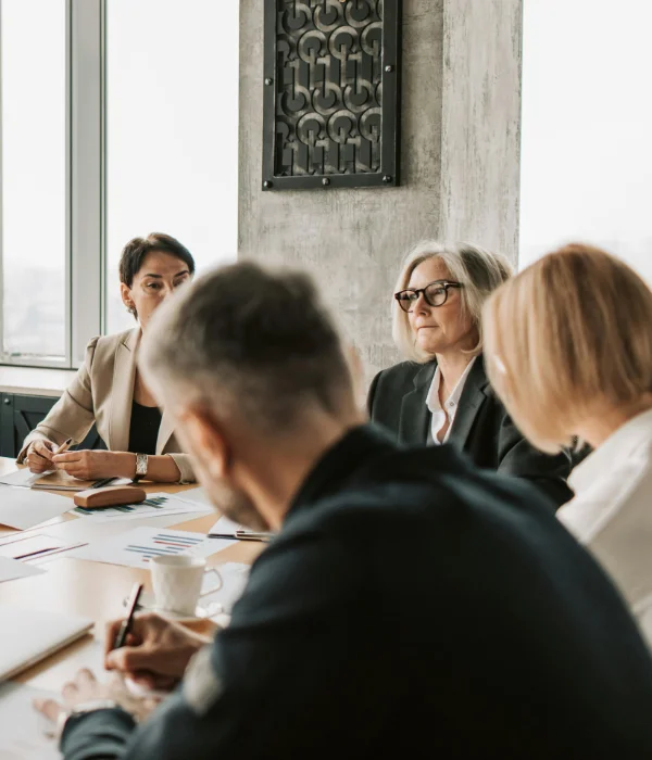 Four business people having a serious discussion during a meeting around a table with papers and coffee.