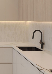 Minimalist kitchen sink with black faucet, white countertop, and light wood cabinets.
