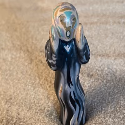 Small figurine resembling Edvard Munch's The Scream with hands on cheeks and open mouth.