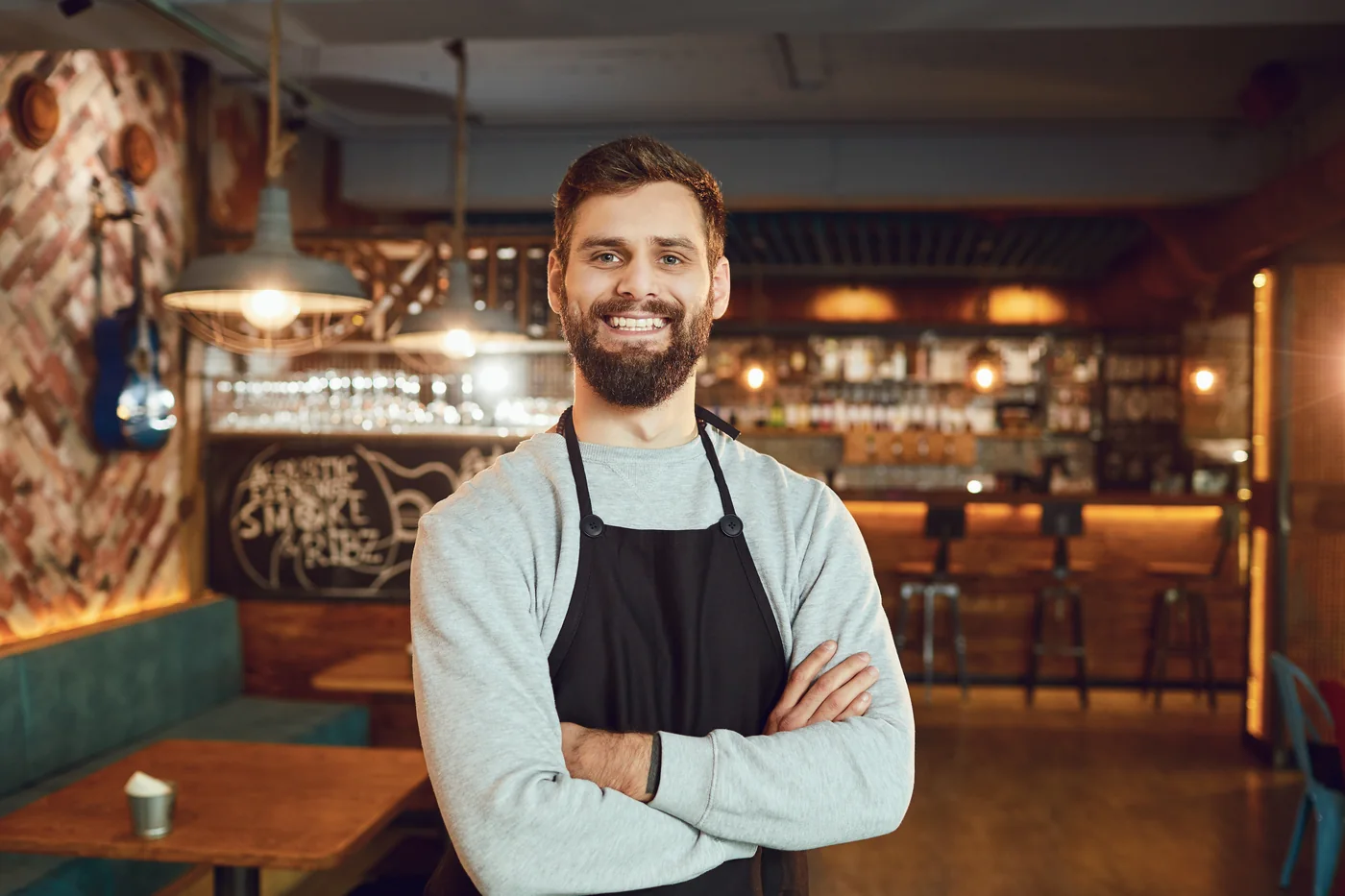Restaurant owner standing with arms crossed in the dining room.