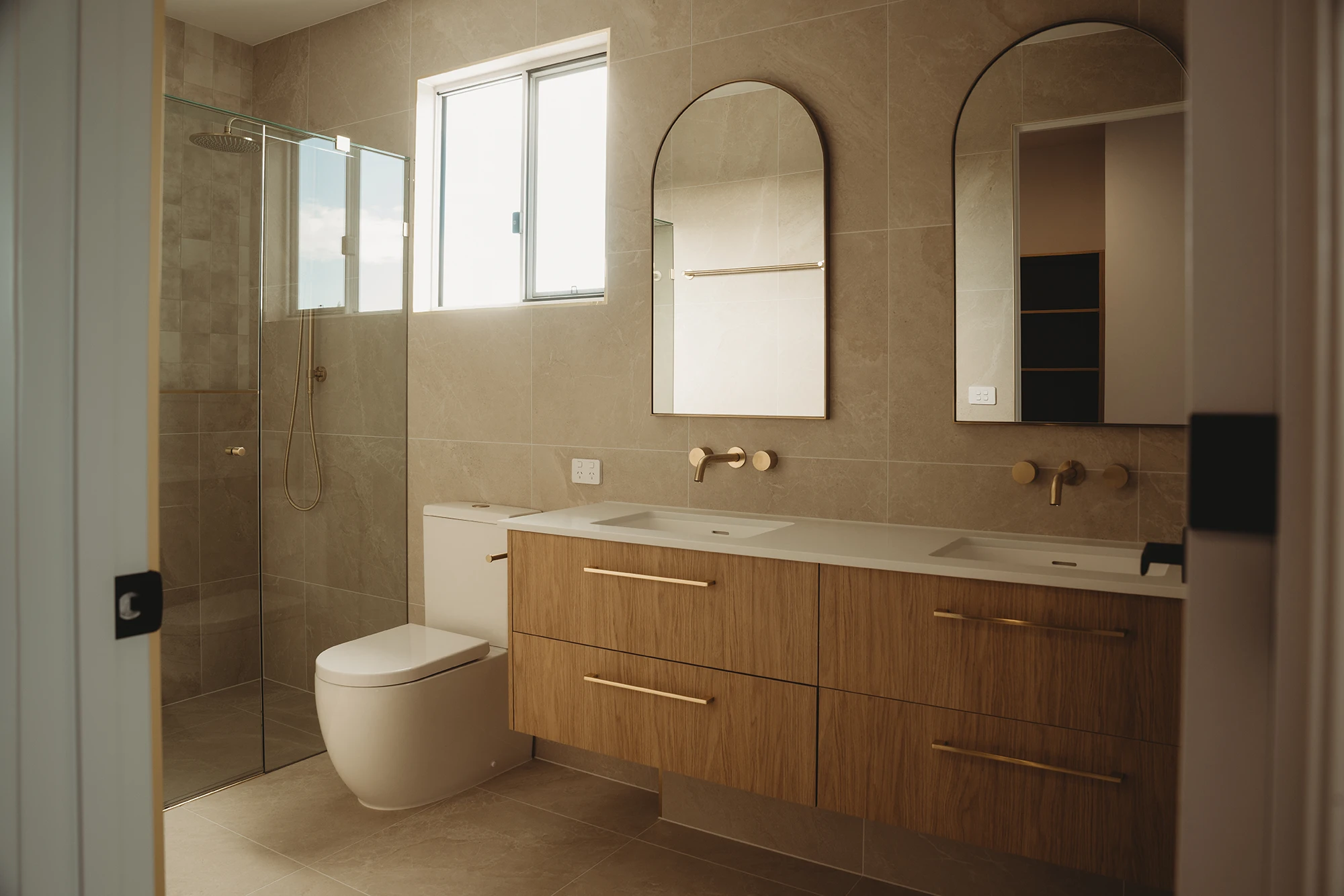 Bathroom with double vanity and brass fixtures inside Eden by Nella