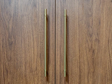Close up of timber cabinetry with brushed brass handles, showing the material detailing of the Vela design.
