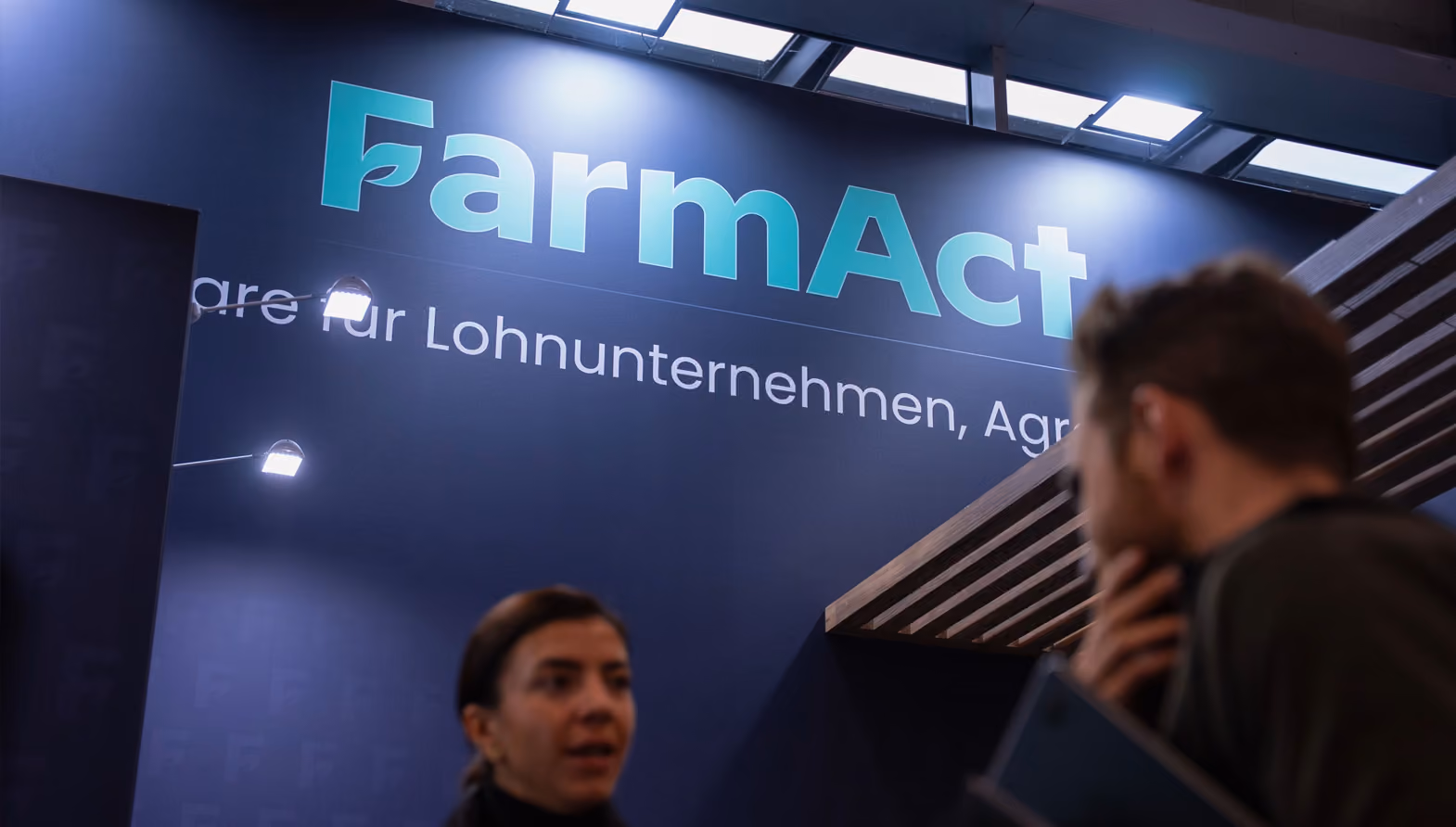 Besucher im Gespräch vor der FarmAct Messewand