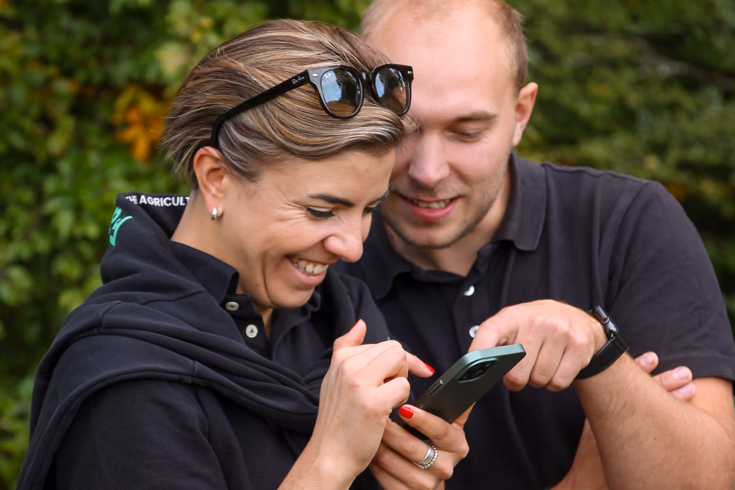 Zwei Mitarbeitende betrachten auf dem Handy die FarmAct App