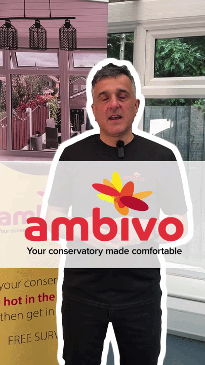 A man with short dark hair stands inside a bright conservatory with large windows and greenery outside, wearing a black shirt. An overlay text shows the Ambivo logo with the tagline 'Your conservatory made comfortable.'
