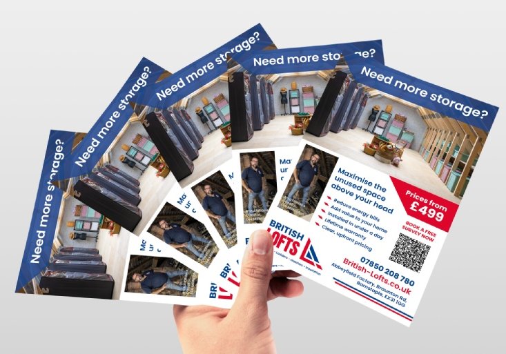 A hand holding five fanned British Lofts promotional flyers showing home loft storage solutions with neatly organized storage units and text offering storage maximization and prices from £499.