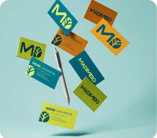 Colorful business cards with MADIMBO and GENE LIKHANYA logos scattered with a silver pen on light blue surface.