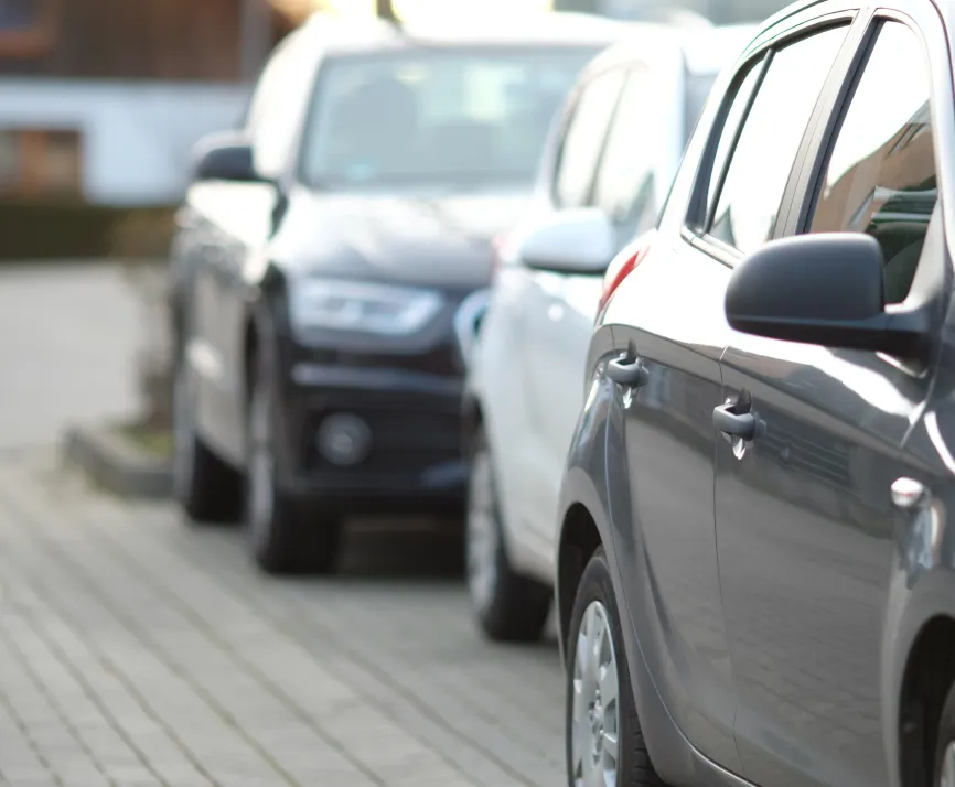 Three cars parked in a row along a paved street, with the closest car in focus.