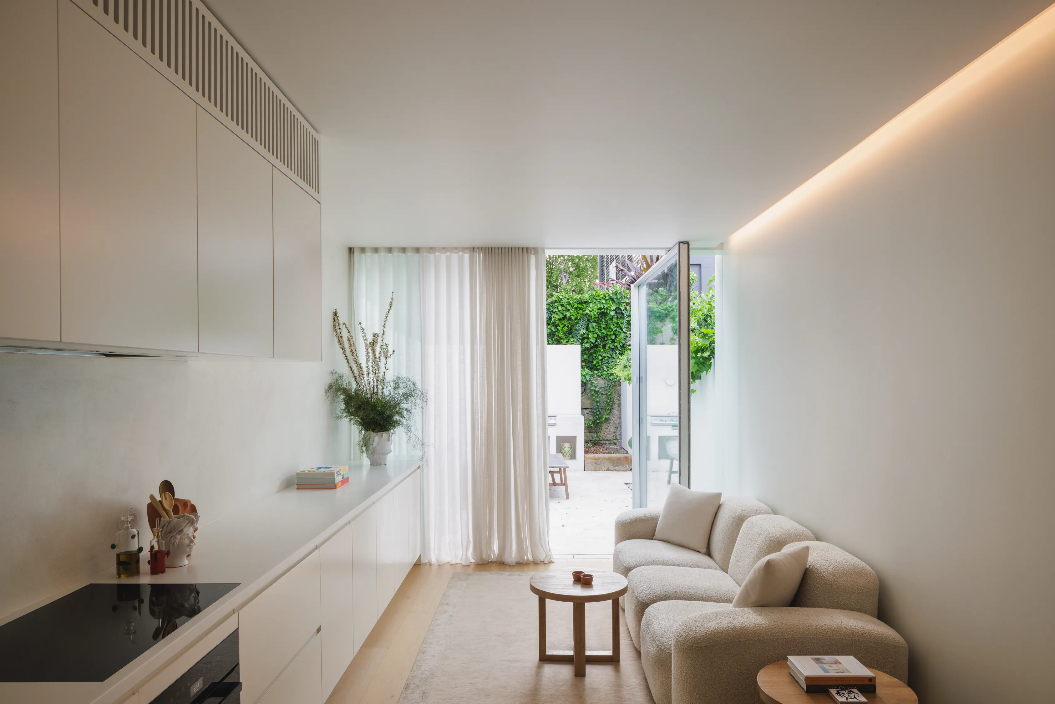 Bright contemporary home interior with a minimalist kitchen, lounge area, and courtyard access.