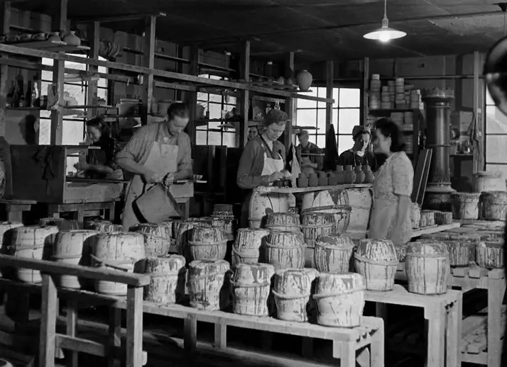 Sort-hvidt billede af kvinder, der arbejder i en keramisk fabrik med krukker og potter.
