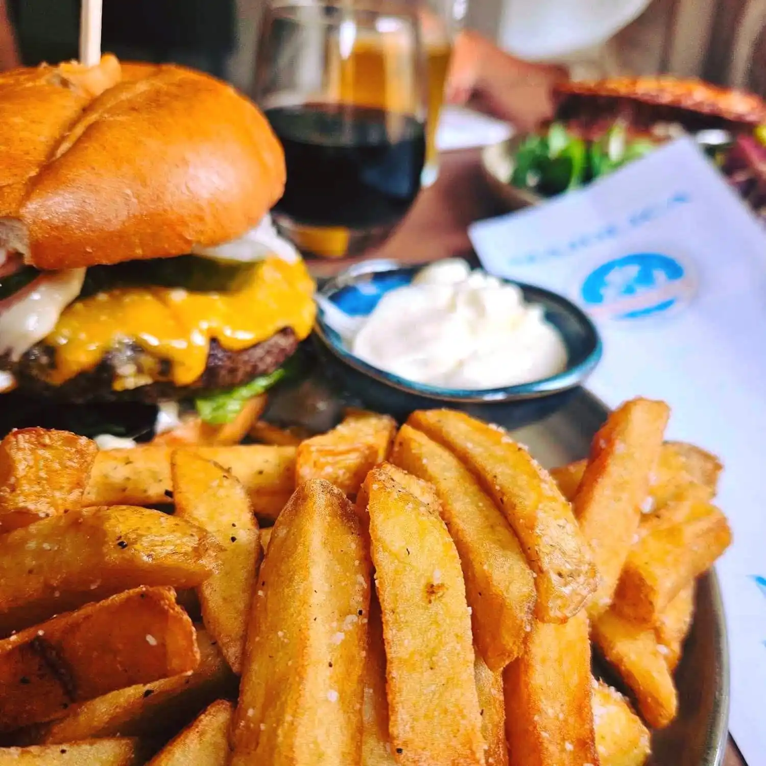 Fedtmættede pommes frites med en cheeseburger og mayonnaise på en tallerken.