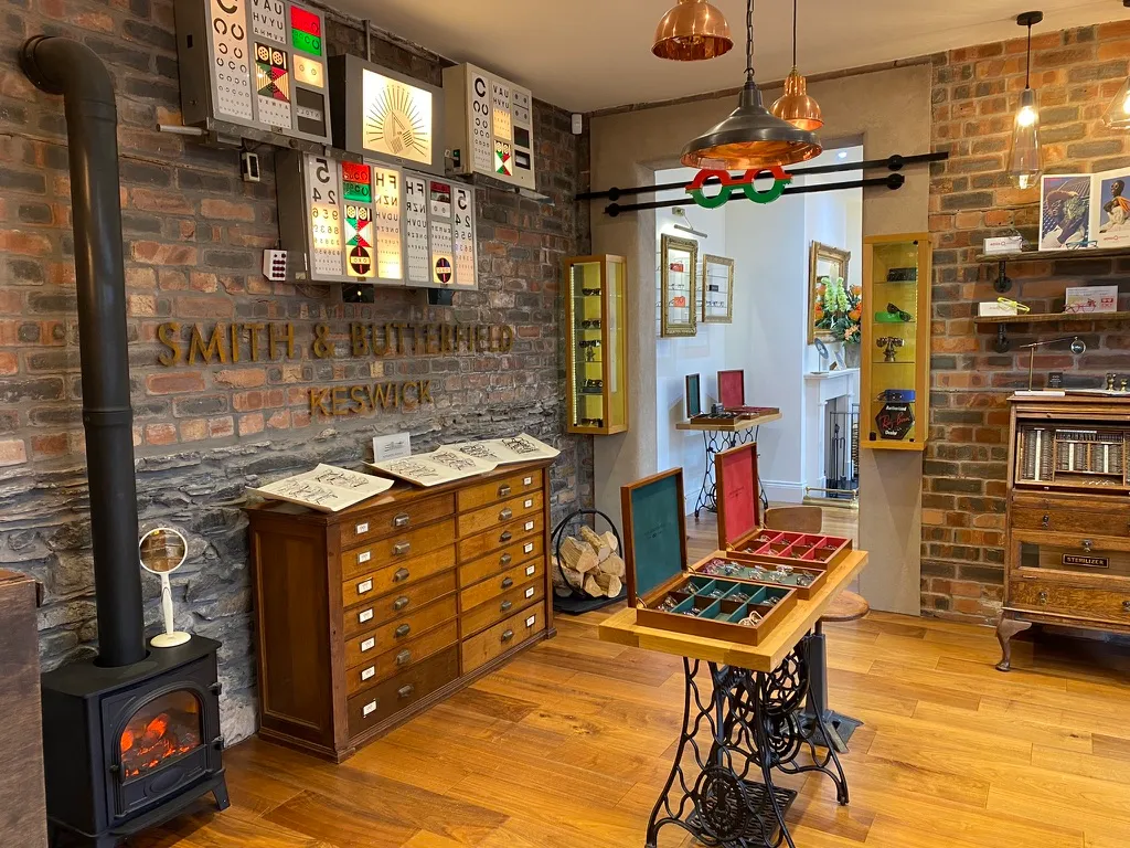Cozy optician interior with wooden floors, eye test charts, display cabinets, and a wood stove.