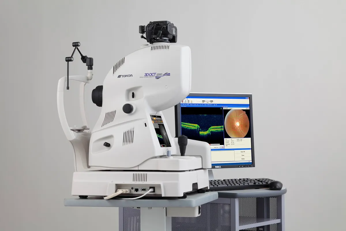 Topcon 3D OCT 2000 eye scanner with monitor showing retinal scan images on a desk.