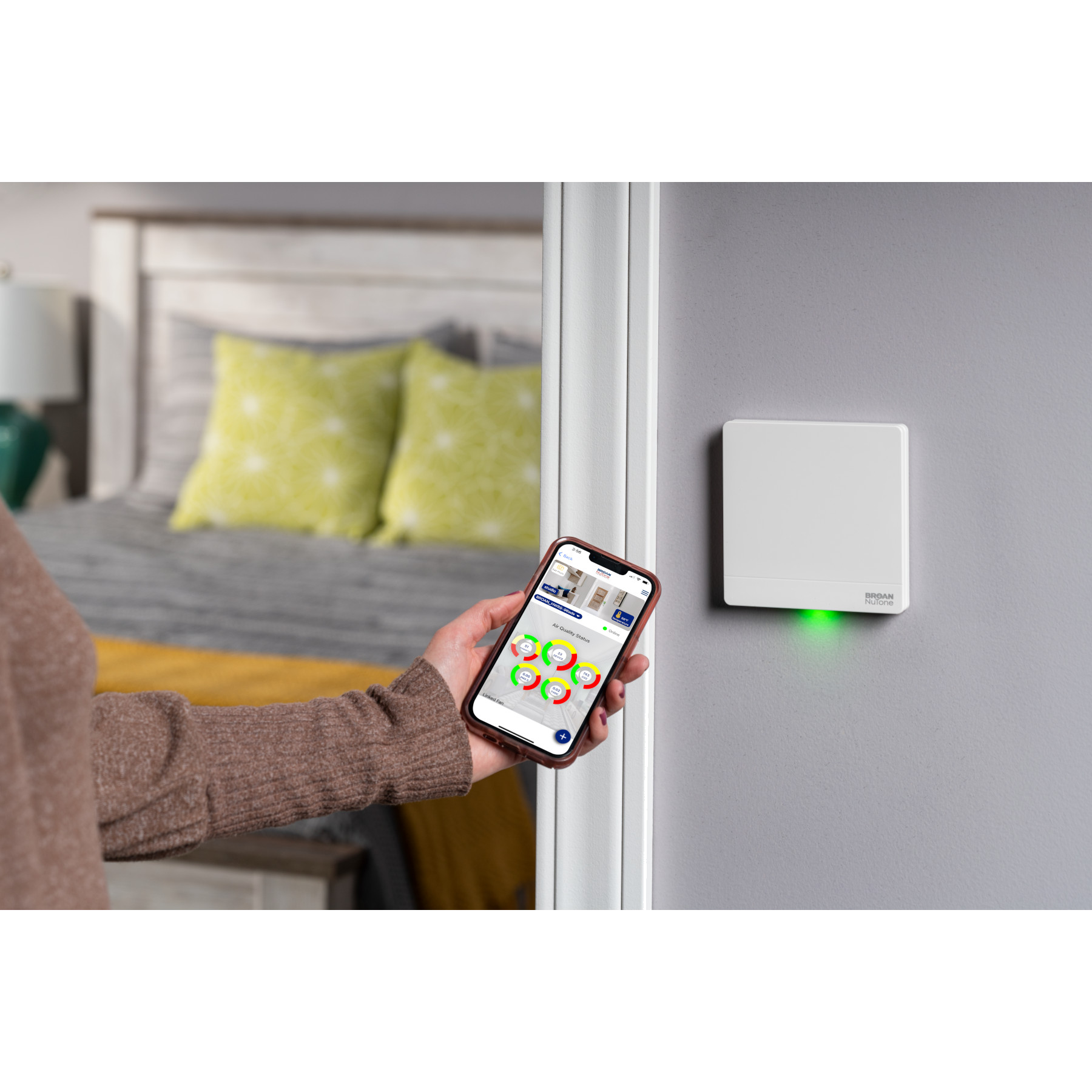 Overture app held beside a wall-mounted Hardwired Room Sensor