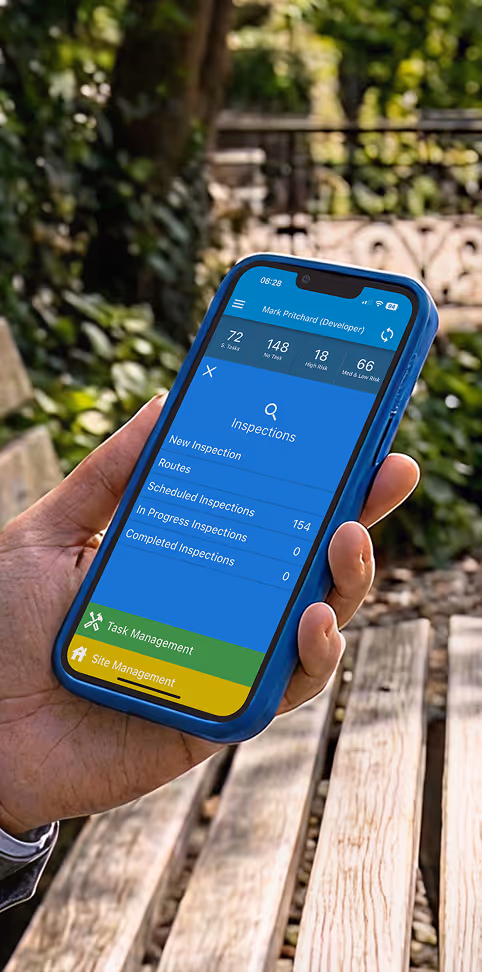 Hand holding phone showing inspection app with task and site management options outdoors.
