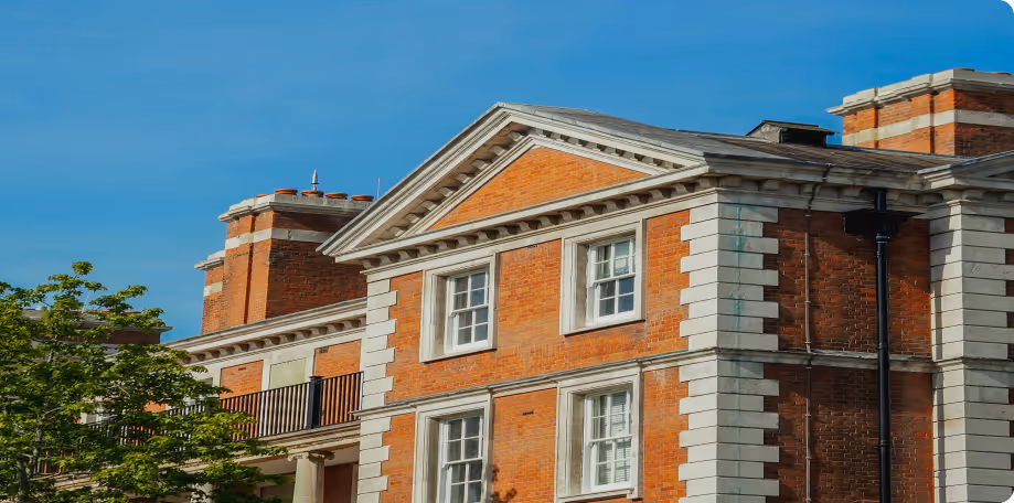 Brick building with white stone trim and chimneys under clear blue sky.