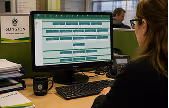 Woman viewing a spreadsheet on a desktop computer in an office setting.