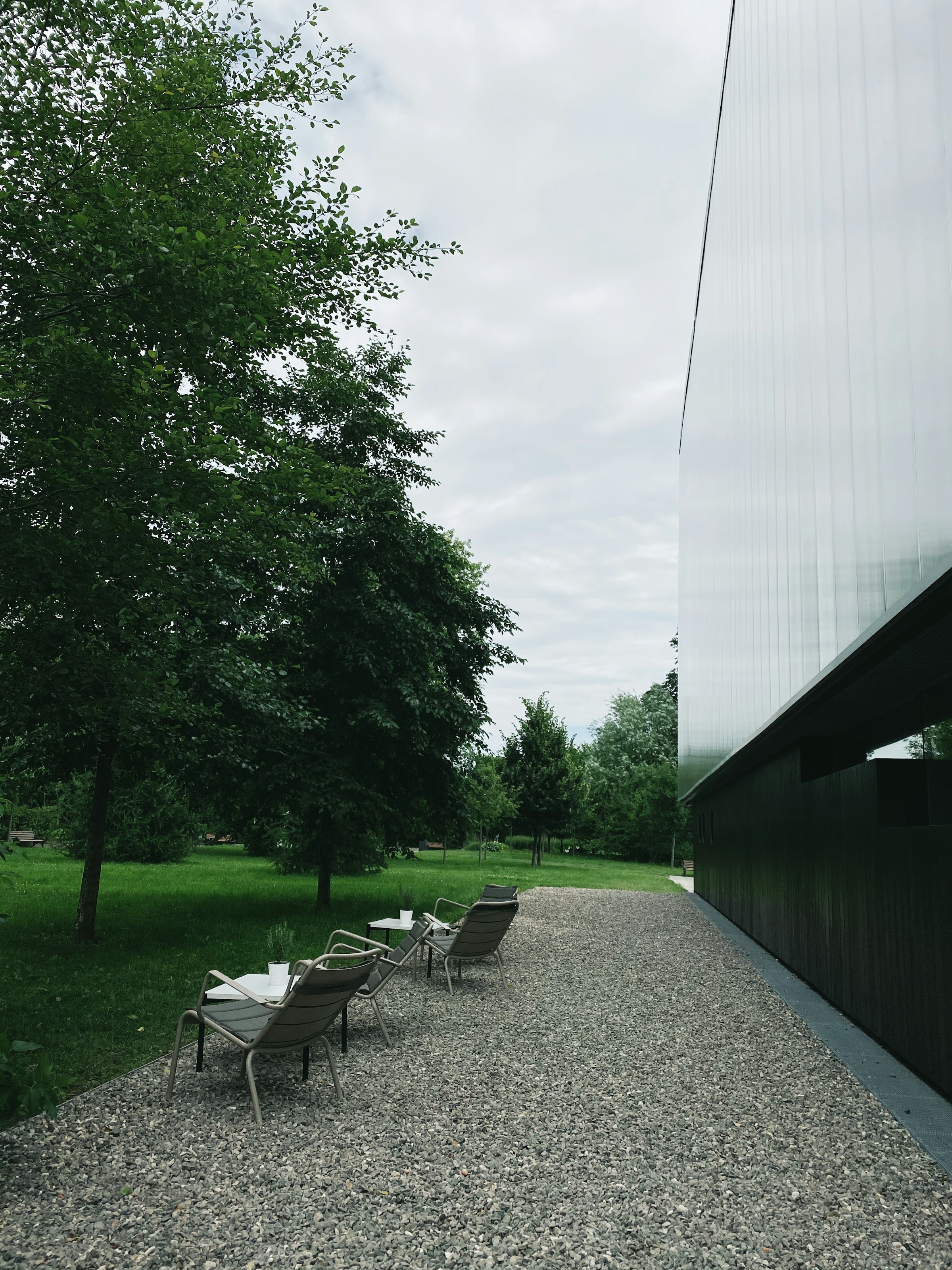 Diseño de espacio exterior con zona de descanso, pavimento de grava y vegetación integrada junto a una vivienda contemporánea.