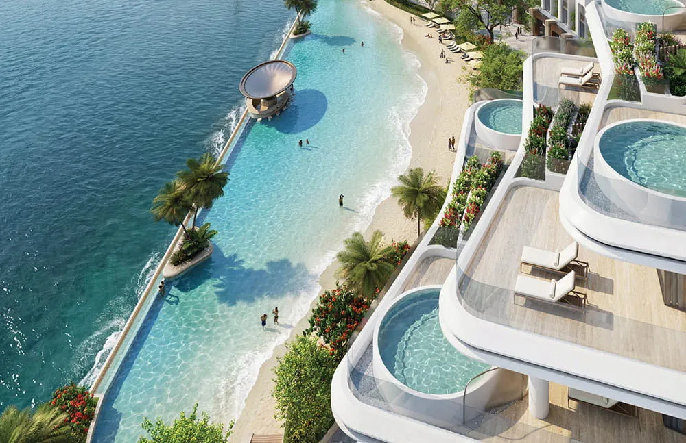 High-angle view of luxury apartment balconies with private plunge pools overlooking a clear blue beach and sea