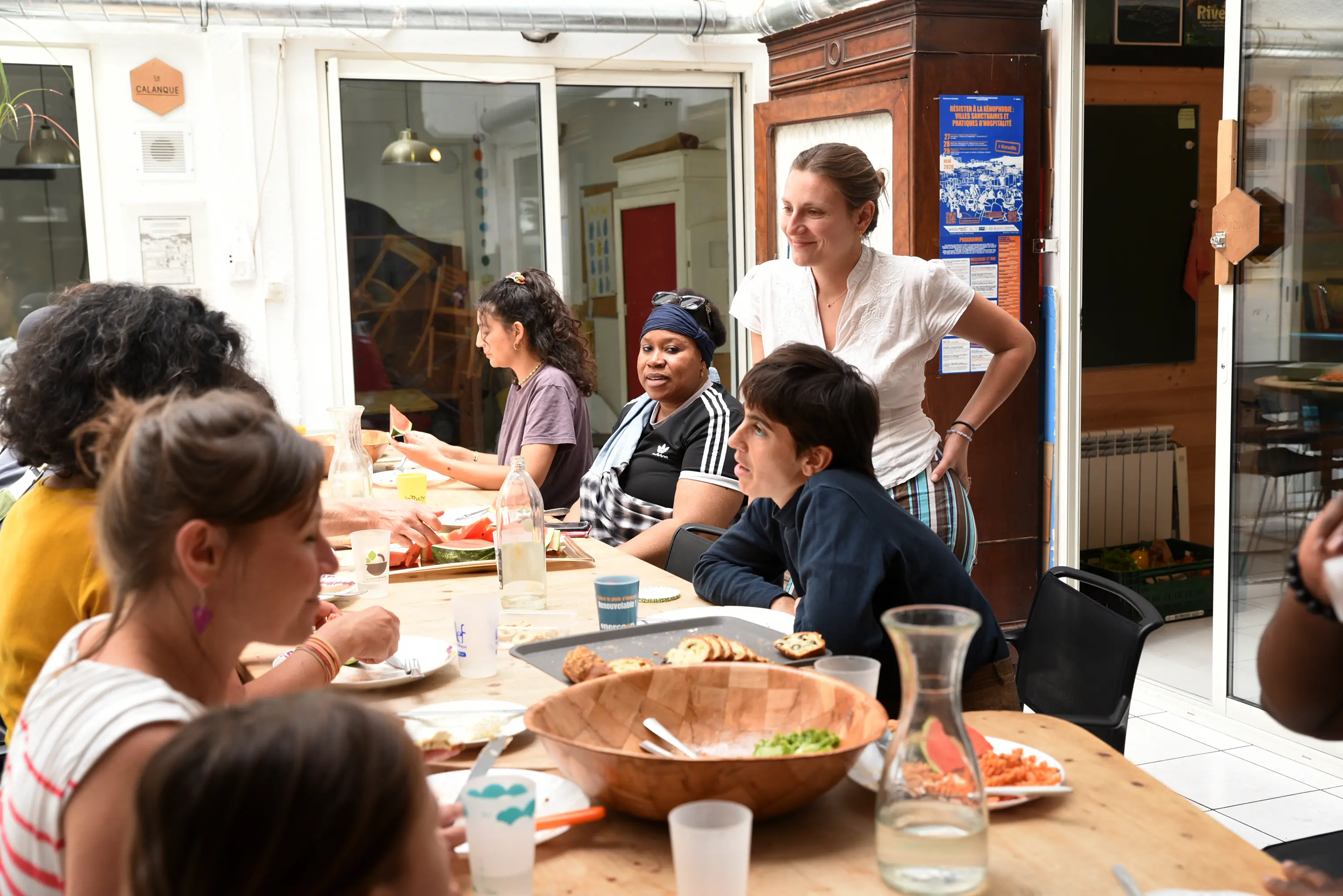 Groupe de personnes partageant un repas convivial autour d'une table en bois lumineuse.