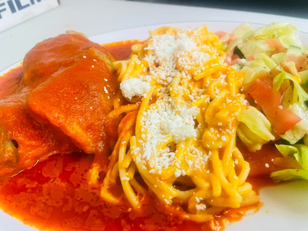 Plate of spaghetti with red sauce, meatballs, and a side salad with lettuce and tomato.