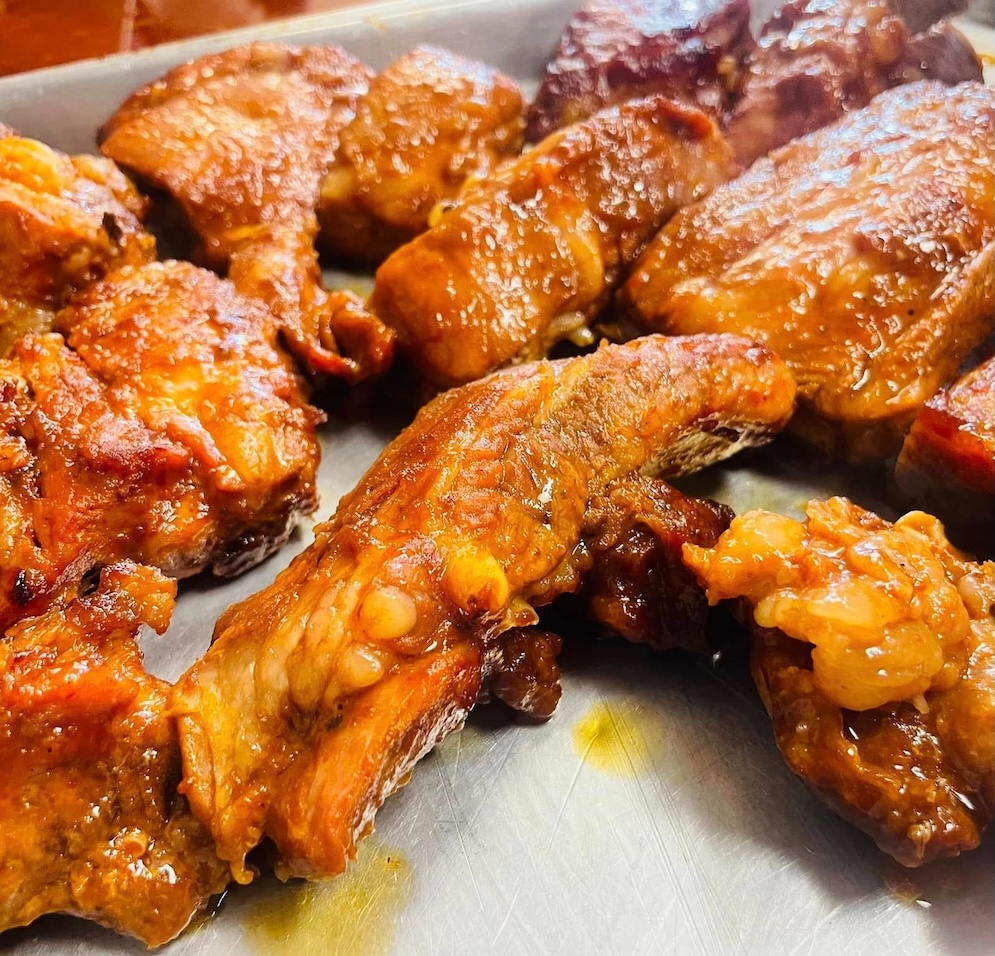 Close-up of glazed, cooked chicken wings on a metal tray.