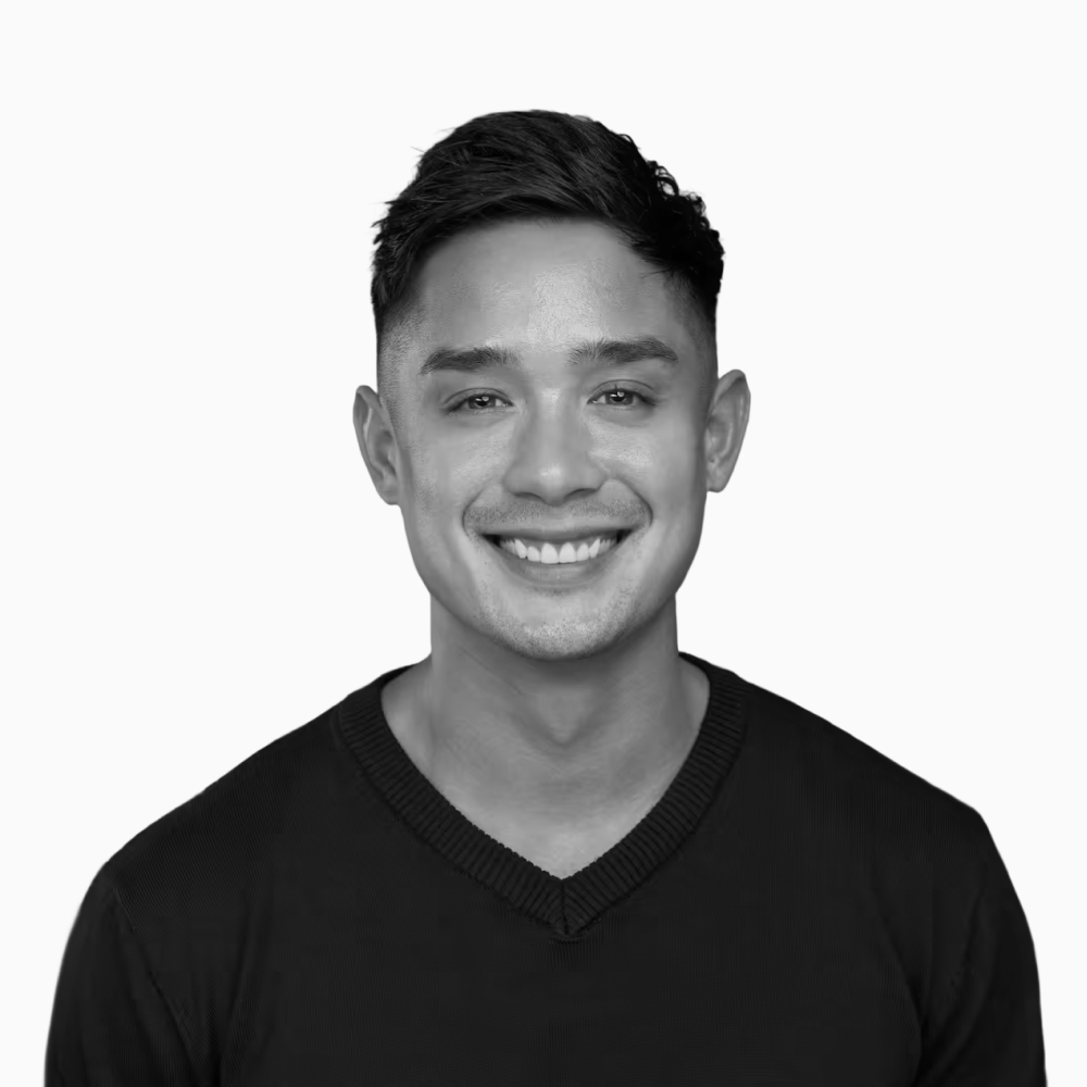 Professional black and white headshot of Kevin, Founder at Key Outreach, smiling while wearing a black sweater against a light gray background.