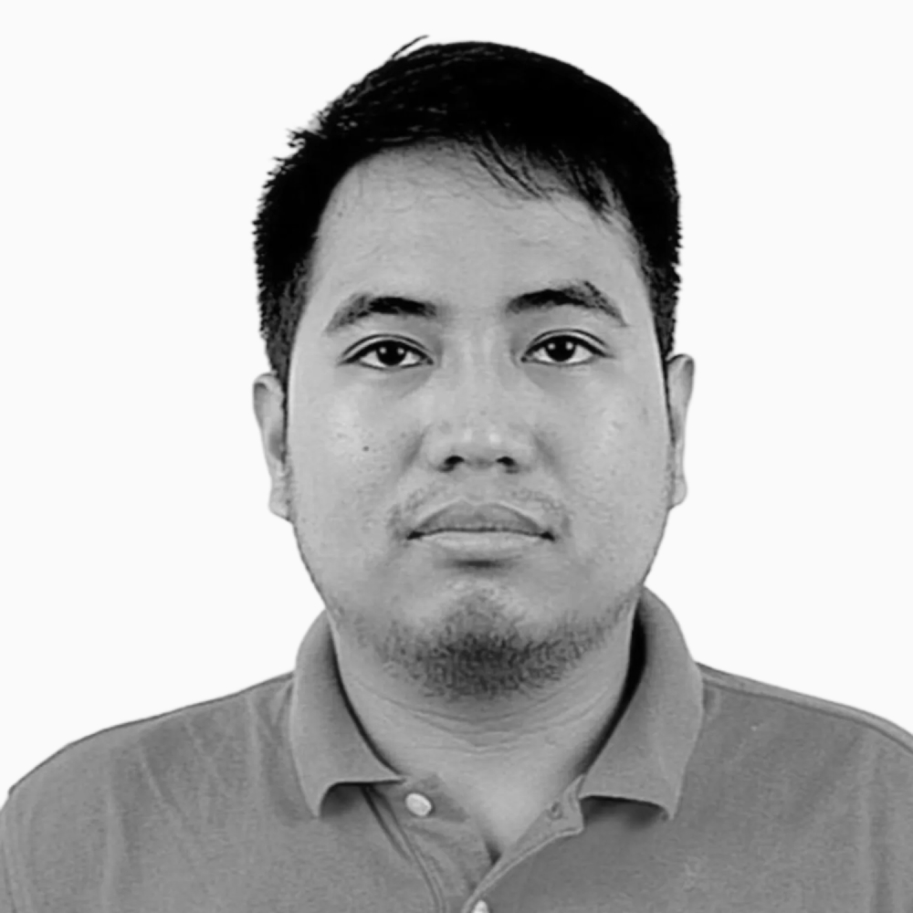 Professional black and white headshot of Neil, Sales Development Manager at Key Outreach, wearing a collared polo shirt while posing against a light gray background.