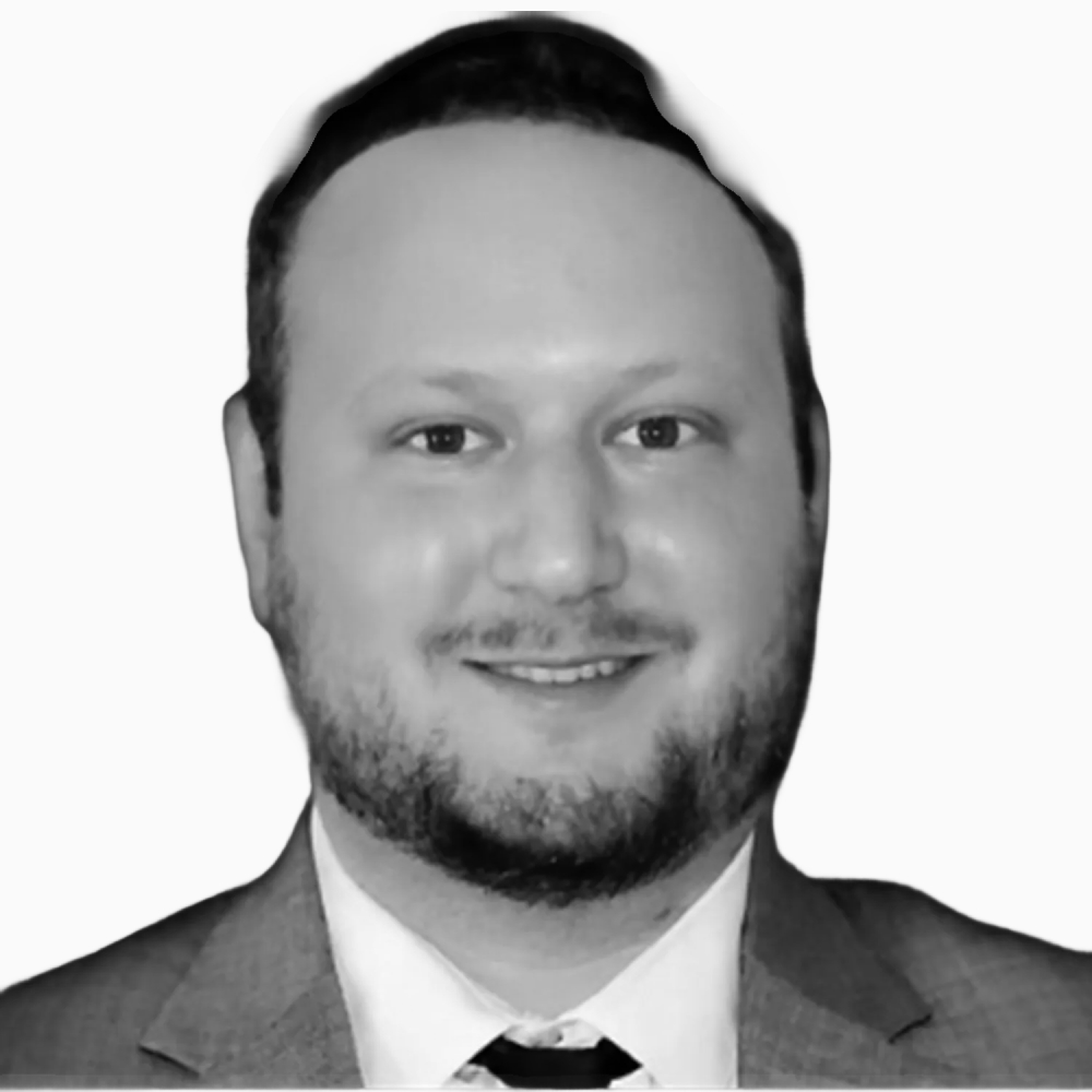 Professional black and white headshot of Paul, Staff Accountant at Key Outreach, smiling while wearing a suit jacket, dress shirt, and tie against a light gray background.