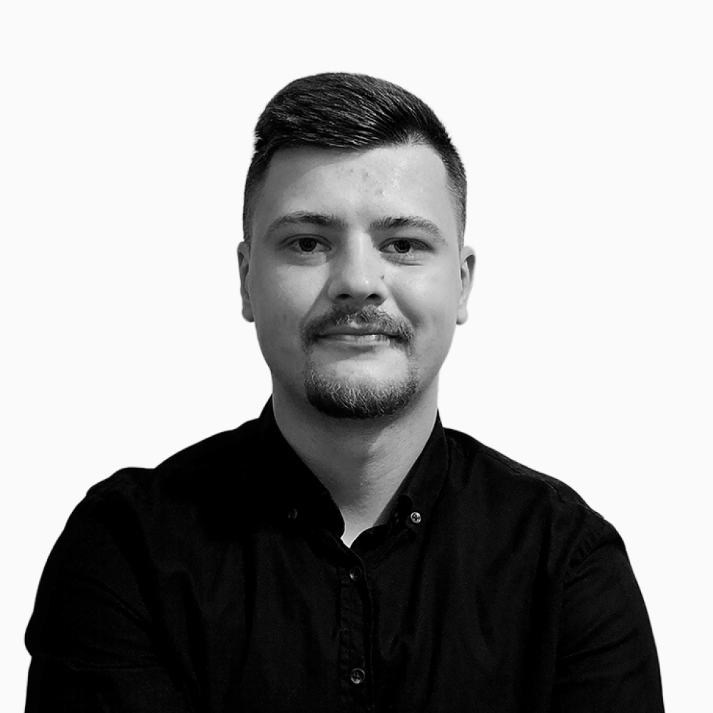 Professional black and white headshot of Sava, Client Success Representative at Key Outreach, smiling while wearing a dark button-up shirt against a light gray background.