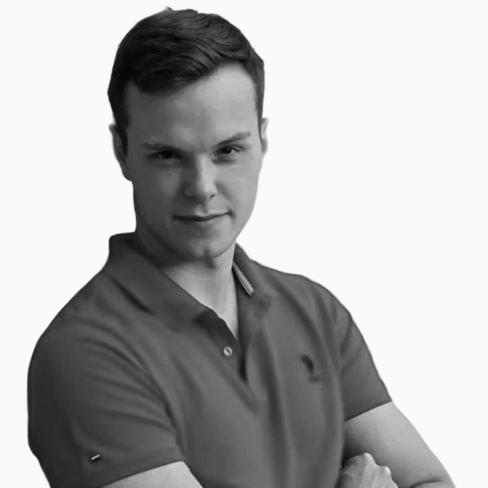 Professional black and white headshot of Zach, Sales Development Representative at Key Outreach, posing with arms crossed while wearing a dark polo shirt against a light gray background.